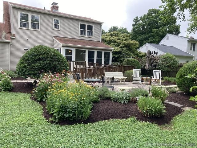 rear view of house with a deck, a lawn, and a patio