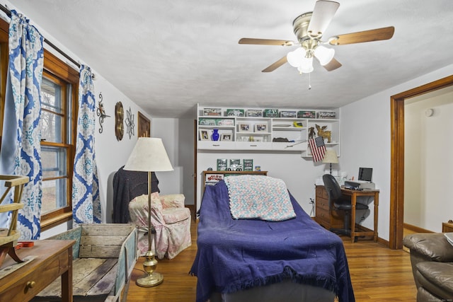 living room featuring ceiling fan, wood-type flooring, and a textured ceiling