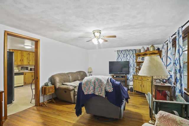 living room with ceiling fan, a textured ceiling, and hardwood / wood-style flooring