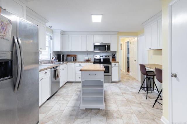 kitchen featuring sink, white cabinetry, a center island, butcher block countertops, and appliances with stainless steel finishes