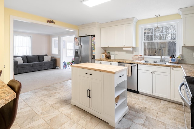 kitchen featuring hanging light fixtures, tasteful backsplash, white cabinets, appliances with stainless steel finishes, and sink