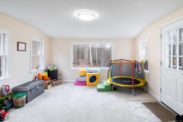 rec room featuring lofted ceiling, a textured ceiling, and light carpet