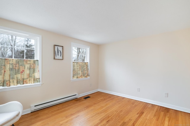 empty room with a healthy amount of sunlight, light hardwood / wood-style flooring, and a baseboard radiator