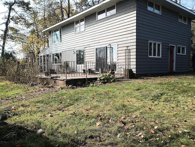 back of property featuring a deck and a yard