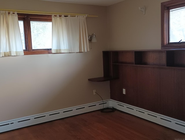 spare room with dark hardwood / wood-style flooring and baseboard heating