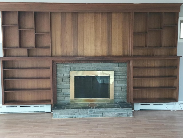 interior details with built in shelves, a baseboard radiator, and hardwood / wood-style floors