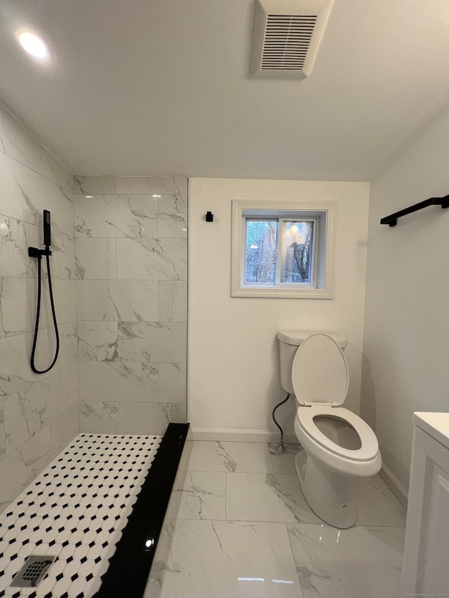 bathroom with tiled shower, vanity, and toilet