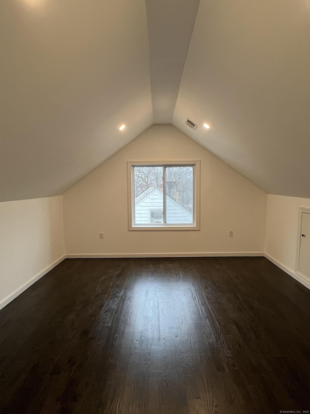 additional living space featuring dark wood-type flooring and vaulted ceiling