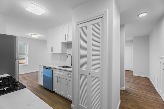 kitchen with dark wood-type flooring, white cabinets, sink, light stone countertops, and appliances with stainless steel finishes