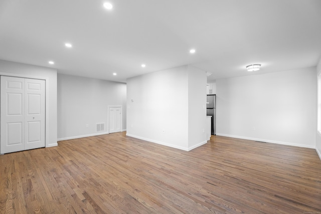 basement featuring stainless steel fridge and light wood-type flooring