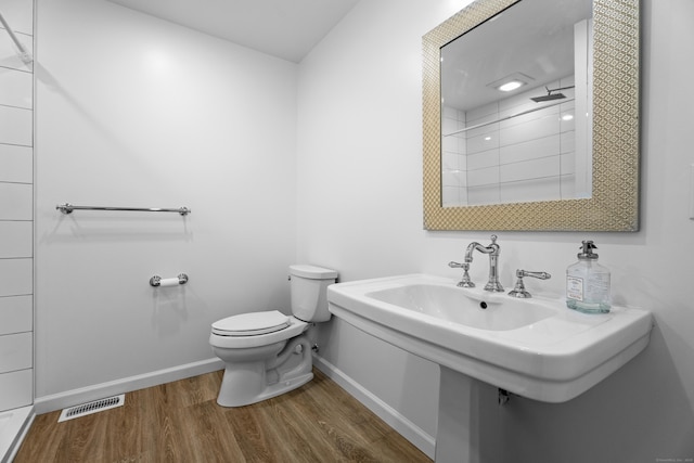 bathroom featuring hardwood / wood-style flooring, toilet, and walk in shower