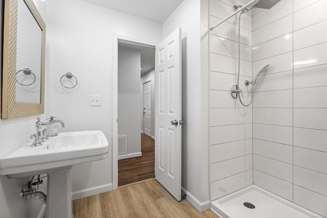 bathroom featuring a tile shower and wood-type flooring