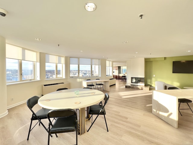 dining space featuring plenty of natural light, light hardwood / wood-style floors, a multi sided fireplace, and radiator