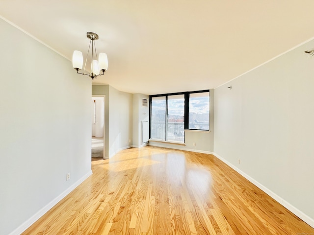 empty room featuring light wood-type flooring and an inviting chandelier