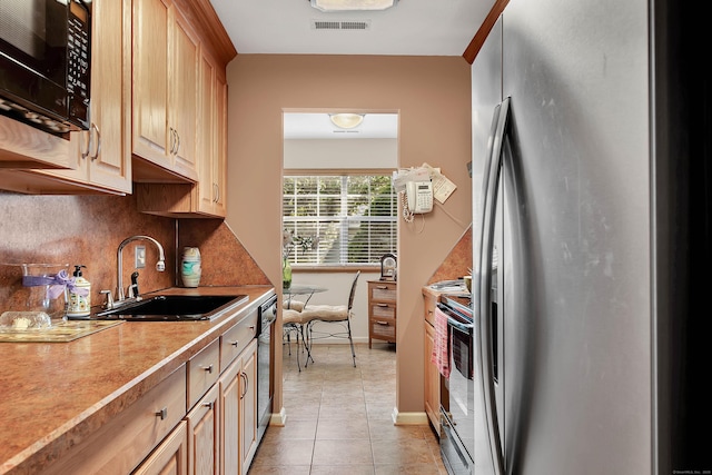 kitchen featuring sink, light brown cabinets, stainless steel appliances, tasteful backsplash, and light tile patterned floors