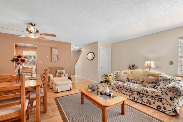 living room with a textured ceiling, light wood-type flooring, and ceiling fan