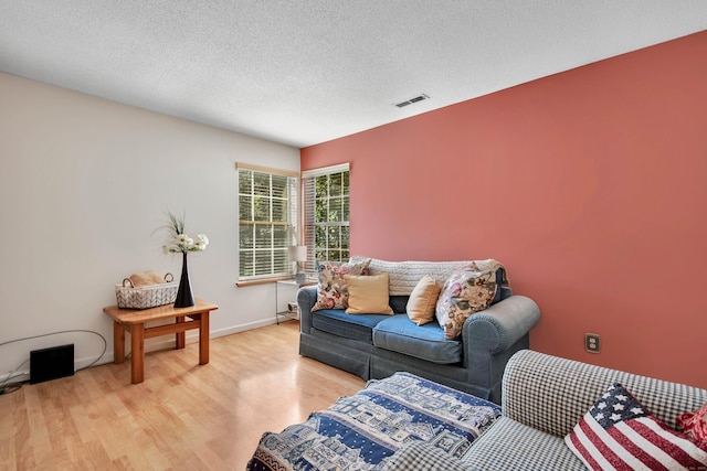 living room with a textured ceiling and light hardwood / wood-style flooring