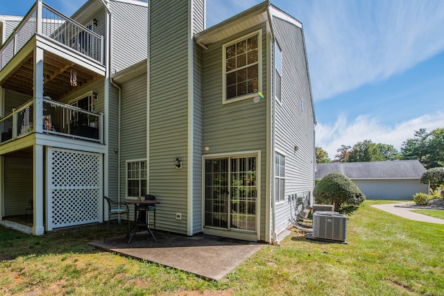 rear view of property with a yard, a patio, a balcony, and central AC