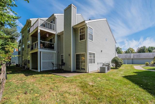 rear view of property featuring central air condition unit, a patio, a balcony, and a lawn