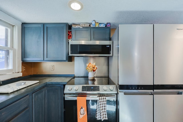 kitchen featuring blue cabinets, a textured ceiling, and appliances with stainless steel finishes