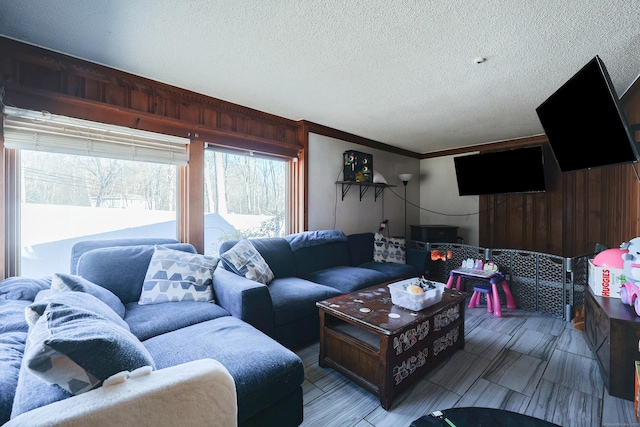 living room with ornamental molding, a textured ceiling, and wooden walls