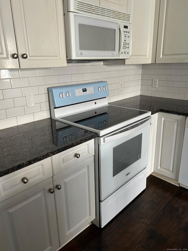 kitchen with backsplash, dark stone counters, white appliances, dark hardwood / wood-style floors, and white cabinetry