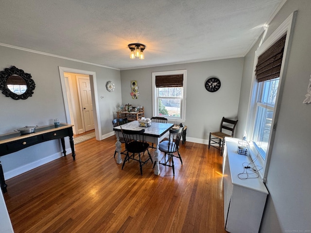 dining space with a textured ceiling, hardwood / wood-style floors, and crown molding