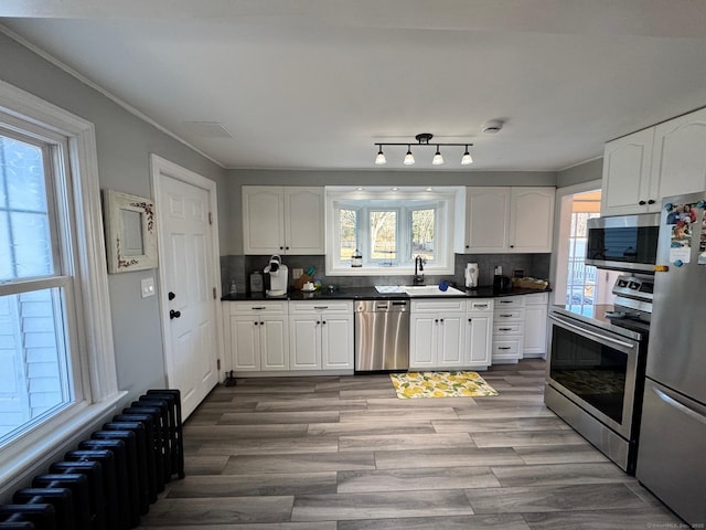 kitchen with radiator, white cabinets, decorative backsplash, and appliances with stainless steel finishes