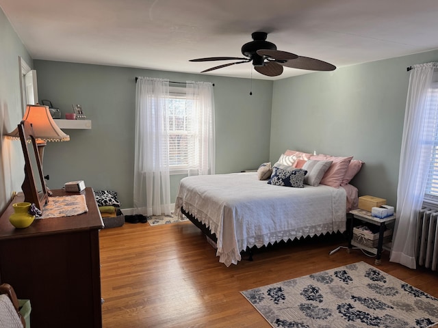 bedroom with wood-type flooring, radiator heating unit, and ceiling fan