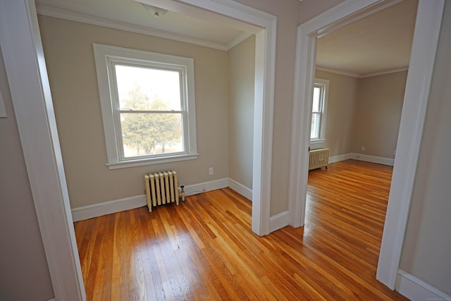 spare room with radiator heating unit, light hardwood / wood-style floors, and ornamental molding