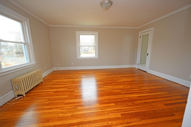 unfurnished room featuring light wood-type flooring, crown molding, radiator, and a baseboard heating unit