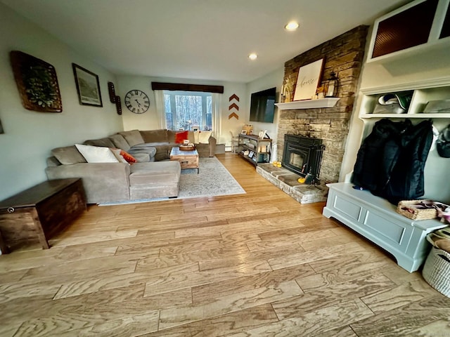 living room with light wood-type flooring and a stone fireplace