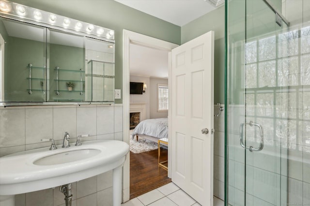 bathroom featuring a shower with shower door, tile walls, decorative backsplash, sink, and tile patterned floors