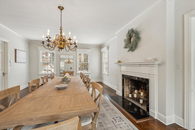 dining space featuring dark hardwood / wood-style flooring, crown molding, a chandelier, and a fireplace