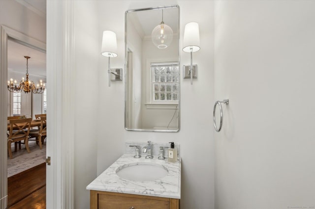 bathroom featuring crown molding, plenty of natural light, a chandelier, and vanity