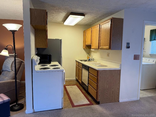 kitchen featuring a textured ceiling, appliances with stainless steel finishes, washer / dryer, carpet floors, and sink