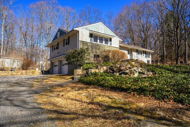 view of front of home featuring a garage, stone siding, and driveway