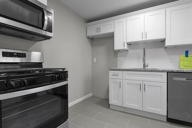 kitchen with sink, stainless steel appliances, light stone counters, backsplash, and white cabinets