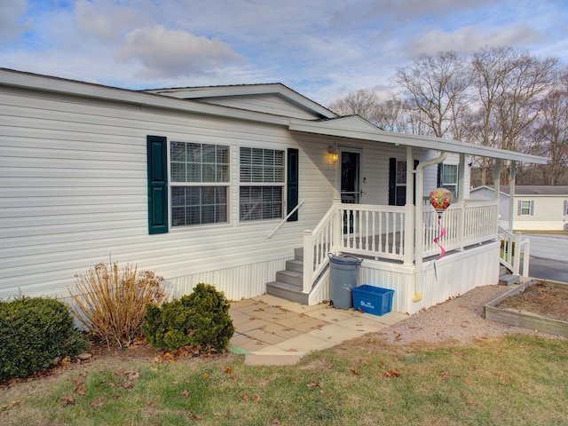 manufactured / mobile home featuring a front yard and a porch