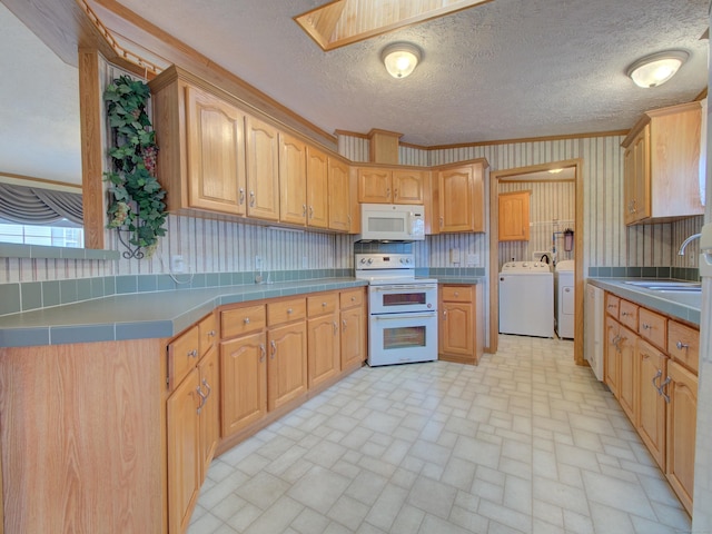 kitchen with a skylight, washer and dryer, white appliances, crown molding, and sink