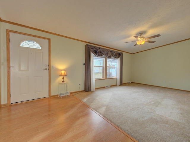 foyer entrance with ceiling fan, crown molding, and light wood-type flooring