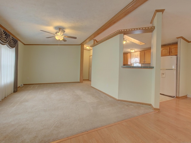 unfurnished living room featuring a textured ceiling, ceiling fan, ornamental molding, and light hardwood / wood-style floors