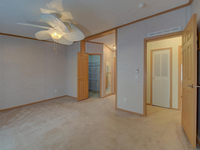 unfurnished bedroom featuring ceiling fan, light carpet, a closet, and ornamental molding