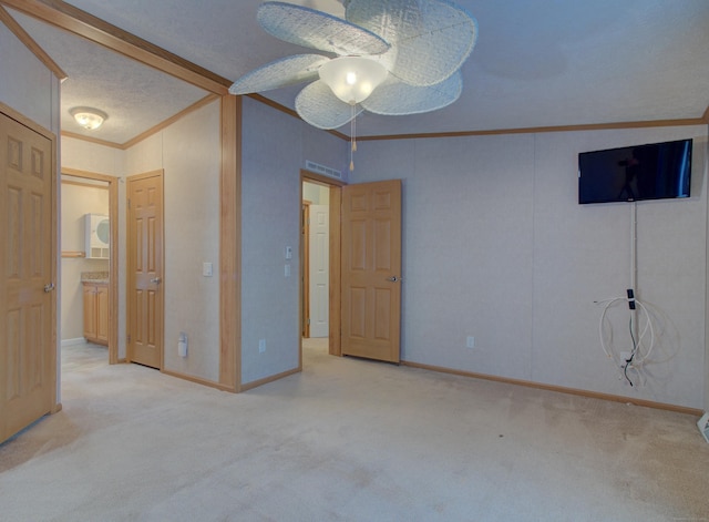 unfurnished bedroom with a textured ceiling, ceiling fan, ornamental molding, and light colored carpet