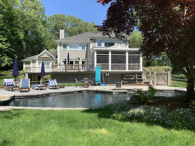 back of property featuring a patio area, a yard, a swimming pool side deck, and a sunroom