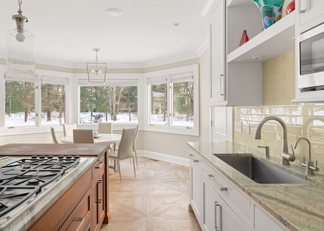 kitchen featuring light stone countertops, pendant lighting, white cabinetry, stainless steel appliances, and sink