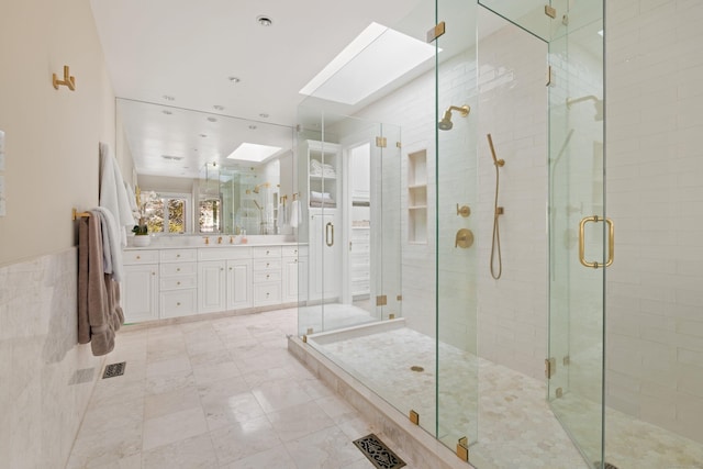 bathroom with vanity, a skylight, tile walls, and a shower with door