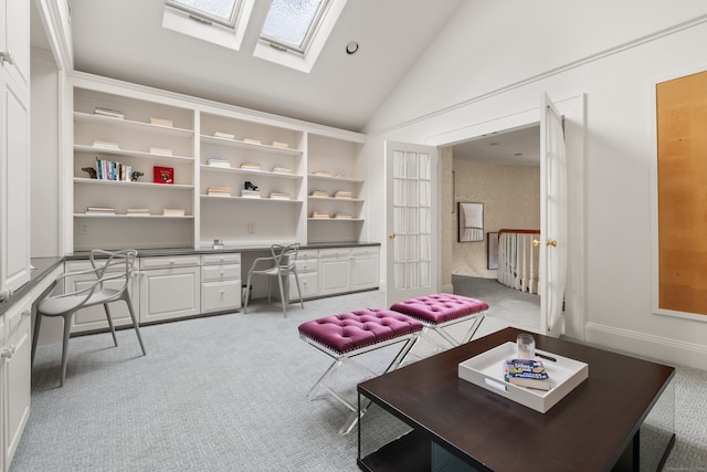 office area with high vaulted ceiling, light colored carpet, a skylight, and built in desk