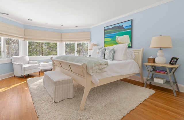 bedroom featuring ornamental molding, light hardwood / wood-style flooring, and multiple windows