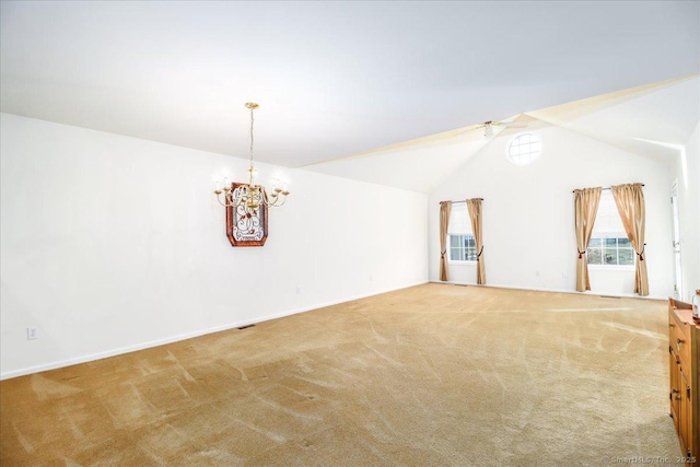 carpeted spare room featuring ceiling fan with notable chandelier and lofted ceiling